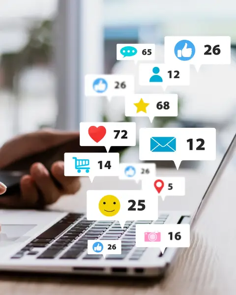 A person working on a laptop with numerous social media notification icons (likes, hearts, messages) floating above the keyboard