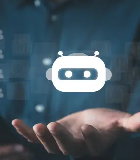 A person holds their hand out, displaying a digital robot icon in a futuristic setting with faint user interface elements in the background.